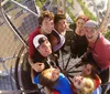 A group of joyful friends takes a selfie from a high vantage point on a sunny day with their faces close together and a parking lot visible below
