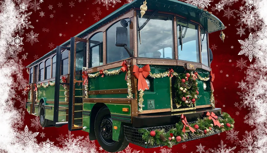 This image showcases a green trolley car festively decorated with holiday wreaths, ribbons, and garland against a red background adorned with white snowflakes.
