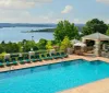 An outdoor swimming pool with loungers overlooks a scenic lake offering a tranquil recreational space