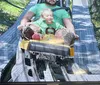 A child and an adult are having a thrilling time while making expressive gestures on a roller coaster ride.