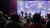 A live music performance is taking place on a brightly lit stage in front of an audience.