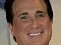 Four individuals are posing for a photo in a movie theater lobby, with two in casual attire flanked by two others dressed in more elaborate, performance-style outfits.