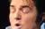 A performer dressed as Elvis Presley is singing on stage with band members and backup singers in the background.