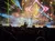 A live band performs on stage with colorful lighting effects in front of an audience.