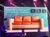 A musician plays the guitar on stage beside an orange sofa with a background featuring text that humorously suggests bubble wrap was invented to be used as wallpaper.