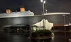 The image shows a large Titanic-themed building, resembling the iconic ship, with a mock iceberg in front, captured at night with a wet parking area reflecting the lights.