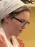 A person in traditional attire is engaged in food preparation in a commercial kitchen, with a barrier and a sign indicating an employee-only area.