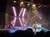A band performs on stage amidst vibrant lighting and an elaborate stage setup.