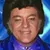 A couple poses for a photo with an entertainer dressed in a flashy blue suit at a 'Legends in Concert' event.