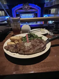 A steak dinner with a side of green beans and potatoes is served in front of a stage with the words