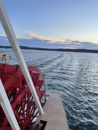 A sunset view over a lake with a paddle wheel boat in the foreground.