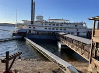 A riverboat is docked at a pier with a walkway leading from the shore to the boat.