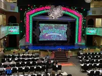The image shows a colorful theater stage set for a