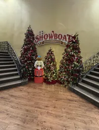The image shows a festive lobby with Christmas trees, a nutcracker decoration, and a sign for