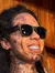A woman poses playfully next to a heavily tattooed figure wearing sunglasses and plaid pants.