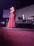 A woman in a red dress is singing on stage with a band accompanying her.