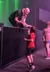 A man with a snake draped around his shoulders interacts with a child in a red shirt at what appears to be a live event or performance.