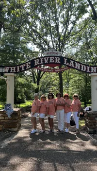 Five women in matching outfits are posing under a