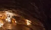 The image shows an underground cave with dim lighting highlighting rock formations and a walkway along the cave floor.