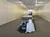 An empty room with track lighting features a small memorial setup, including a table with a white cloth, a plate, an American flag, a rose, and a POW/MIA chair.