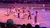 A group of performers dressed in western-style attire is dancing and acting in an arena setting, observed by an audience.