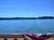 The image shows a view from a boat's railing decorated with an American flag bunting, overlooking a calm body of water under a clear blue sky.