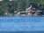 The image shows a barge on the water with a red, rustic building and trees in the background.