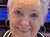 A person poses cheerfully in front of a stage with a