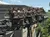 People are riding a roller coaster with a steampunk theme under a clear blue sky.
