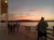 People are enjoying a scenic sunset view from a deck overlooking a calm body of water.