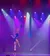 Aerial performers are suspended mid-air with fabric, illuminated by colorful stage lights.