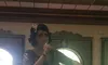 A person dressed in a glamorous outfit is singing into a microphone in a decorated venue.