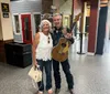 A smiling man holding a guitar and a woman are posing together under a sign that reads 