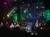 A band is performing on stage, surrounded by colorful lights and a starry backdrop.
