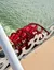 The image shows a red paddle wheel on a boat, partially submerged in water, with decorative railing in the foreground.