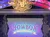 The image shows a stage decorated with ornate designs and a colorful banner reading 