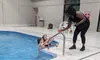 Two people in a swimming pool receive drinks from a person standing by the poolside.