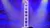 An acrobat is performing a balancing act on a tall stack of chairs, illuminated by colorful stage lights.
