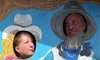 Two people are posing with their faces in cutouts of a cartoon cowboy and cowgirl.