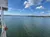 A scenic view of a calm lake under a partly cloudy sky, with a portion of a boat railing visible on the left.