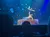 Two acrobats perform a balancing act on a stage with a starry backdrop.