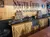 The image shows a wooden bar setup at Smith Creek Moonshine, featuring shelves of moonshine jars with a 