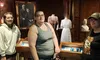 Three people pose in a historical exhibit featuring vintage clothing, a framed photograph, and other artifacts.