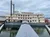 The image shows a large, multi-deck paddlewheel riverboat docked on a cloudy day.