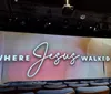 The image shows a stage with a large backdrop displaying the words 