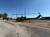 A military helicopter is displayed on a paved area near an empty parking lot under a clear blue sky.