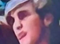 A band performs on stage with a beach-themed backdrop featuring a large image of The Beach Boys and surfboards.