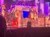 A group of performers dressed as elves are energetically dancing on a festive stage with Christmas decorations.