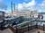 A large paddlewheel riverboat is docked next to a wooden boardwalk on a calm waterway under a partly cloudy sky.