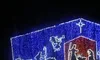 The image features a Christmas nativity scene outlined in colorful lights on a structure, with figures such as Mary, Joseph, and baby Jesus, set beneath a starry background.